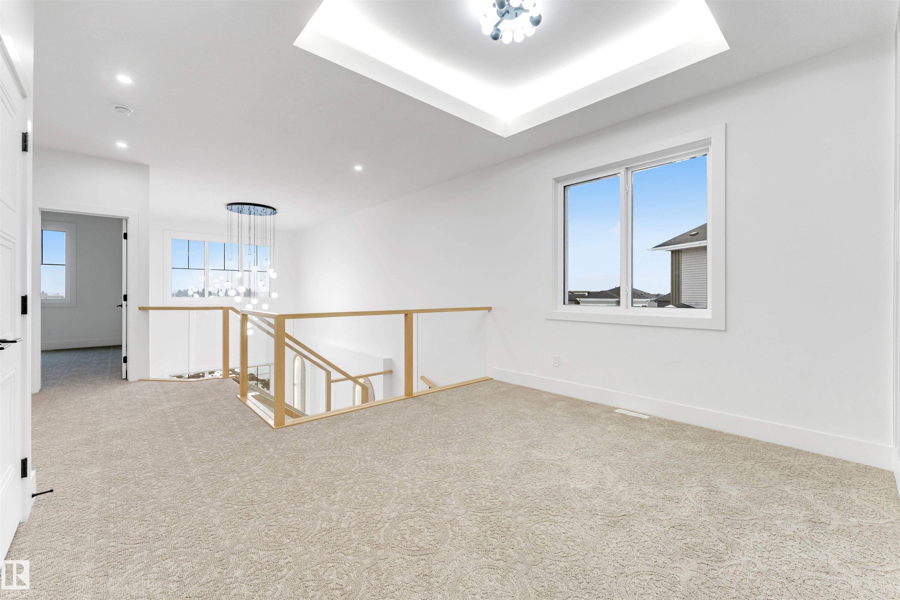 The property features a bright interior with light-colored carpeting, white walls, and a modern chandelier - 4004 35 Street, Beaumont, AB - Indoor Photo Showing Other Room
