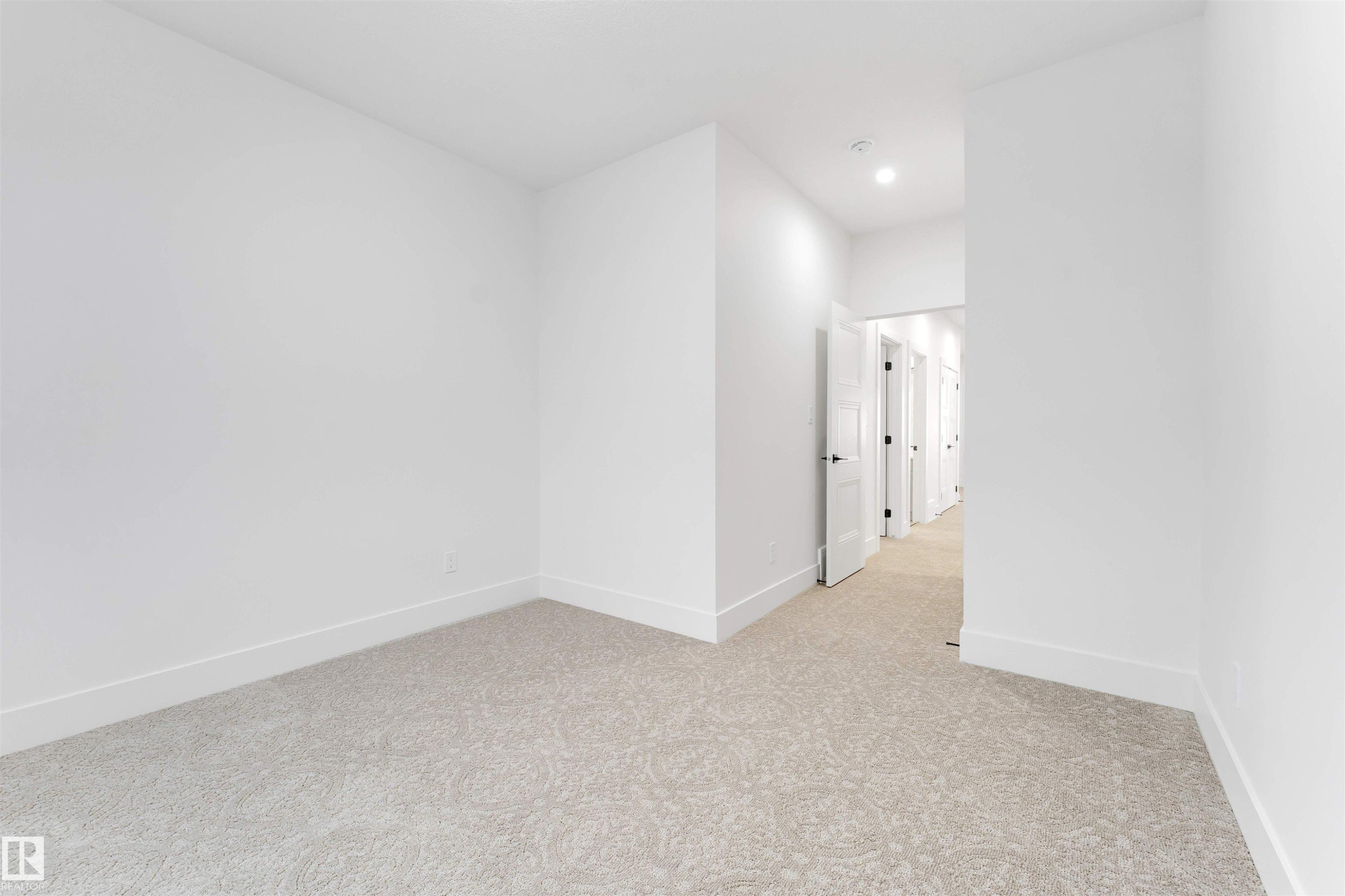 This interior space features light-colored carpeting, white walls, and white baseboards - 4004 35 Street, Beaumont, AB - Indoor Photo Showing Other Room