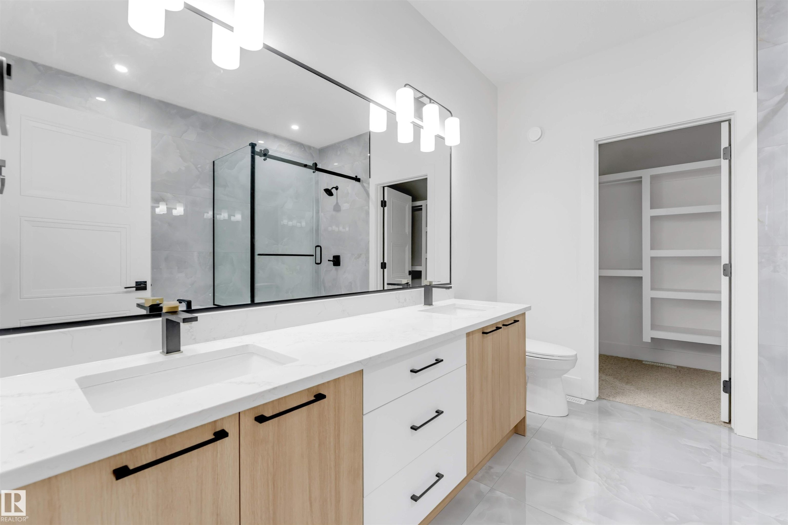 Bathroom featuring a dual vanity with white countertops, light wood and white cabinetry, and matte black hardware - 4004 35 Street, Beaumont, AB - Indoor Photo Showing Bathroom