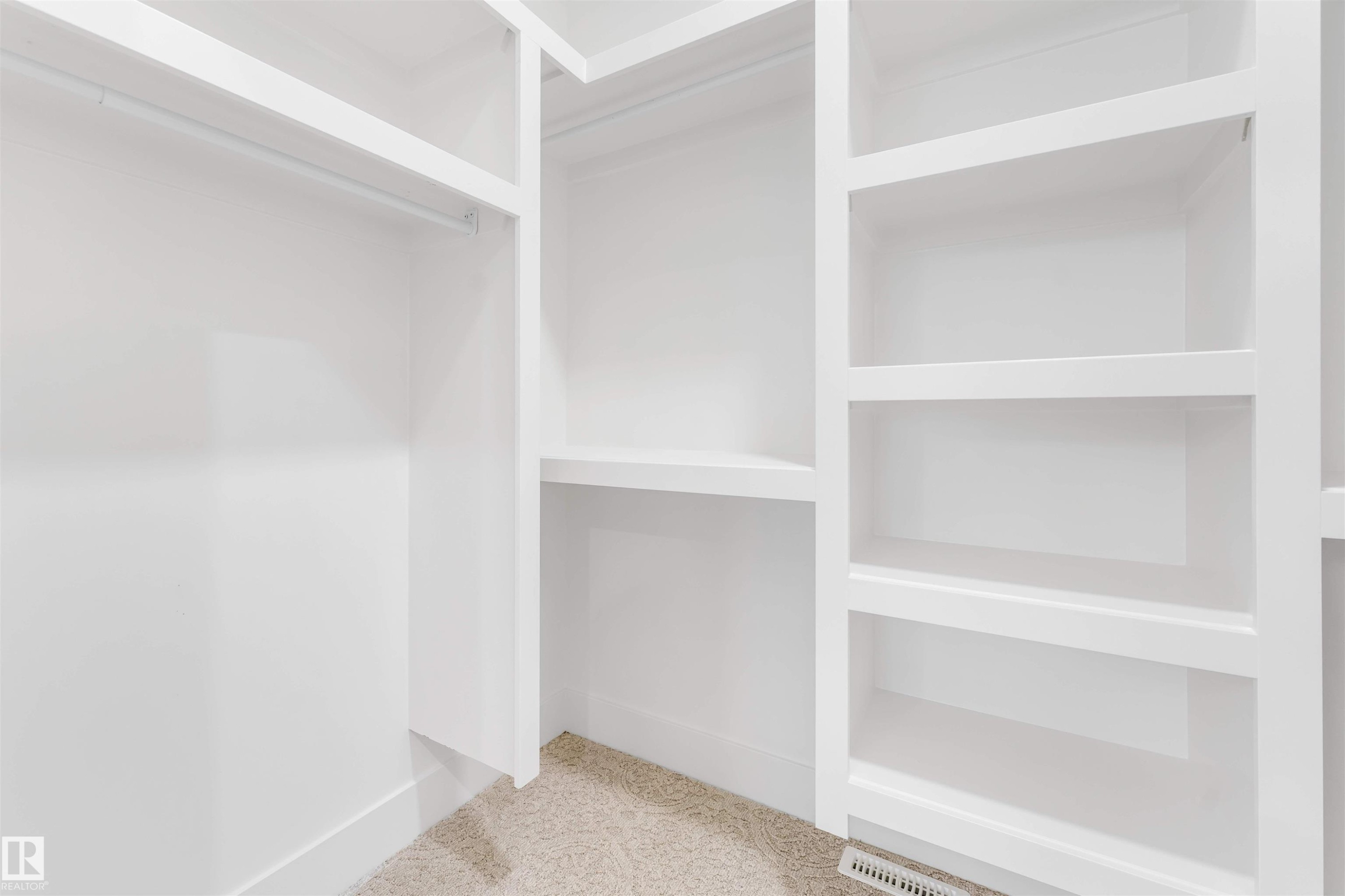 This closet features extensive white built-in shelving, a hanging rod, and carpet flooring - 4004 35 Street, Beaumont, AB - Indoor