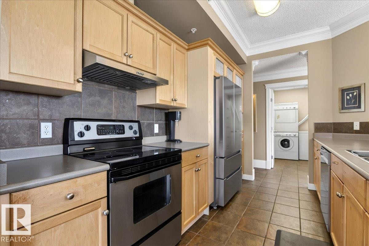 Kitchen featuring light wood cabinetry, stone-finish countertops, stainless steel appliances, and a tiled backsplash - 701 9707 105 Street, Edmonton, AB - Indoor Photo Showing Kitchen