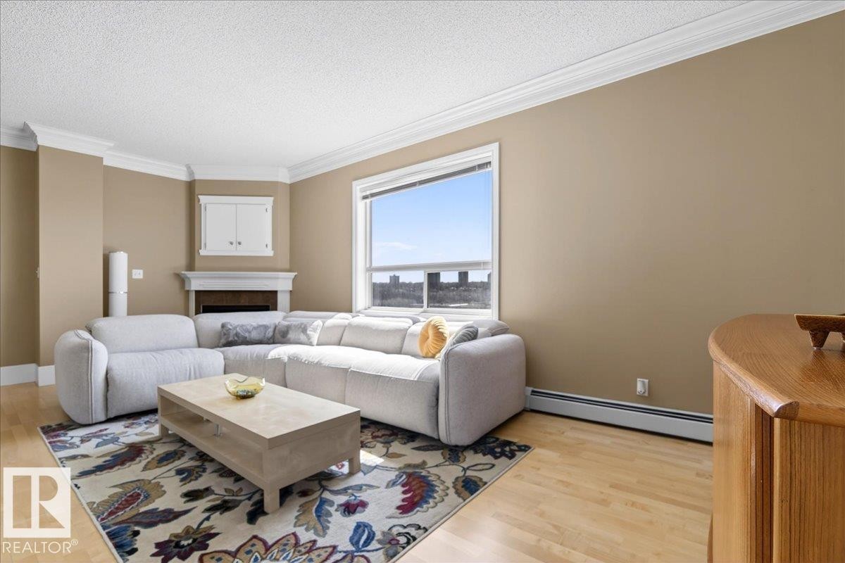 Living area featuring light wood-finish flooring and a corner fireplace with built-in cabinetry - 701 9707 105 Street, Edmonton, AB - Indoor Photo Showing Living Room With Fireplace