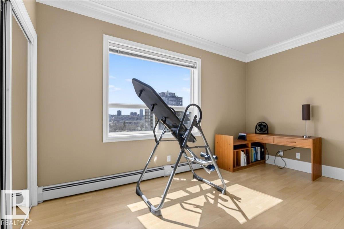 Bright room featuring wood-finish flooring, a large window, and crown molding - 701 9707 105 Street, Edmonton, AB - Indoor