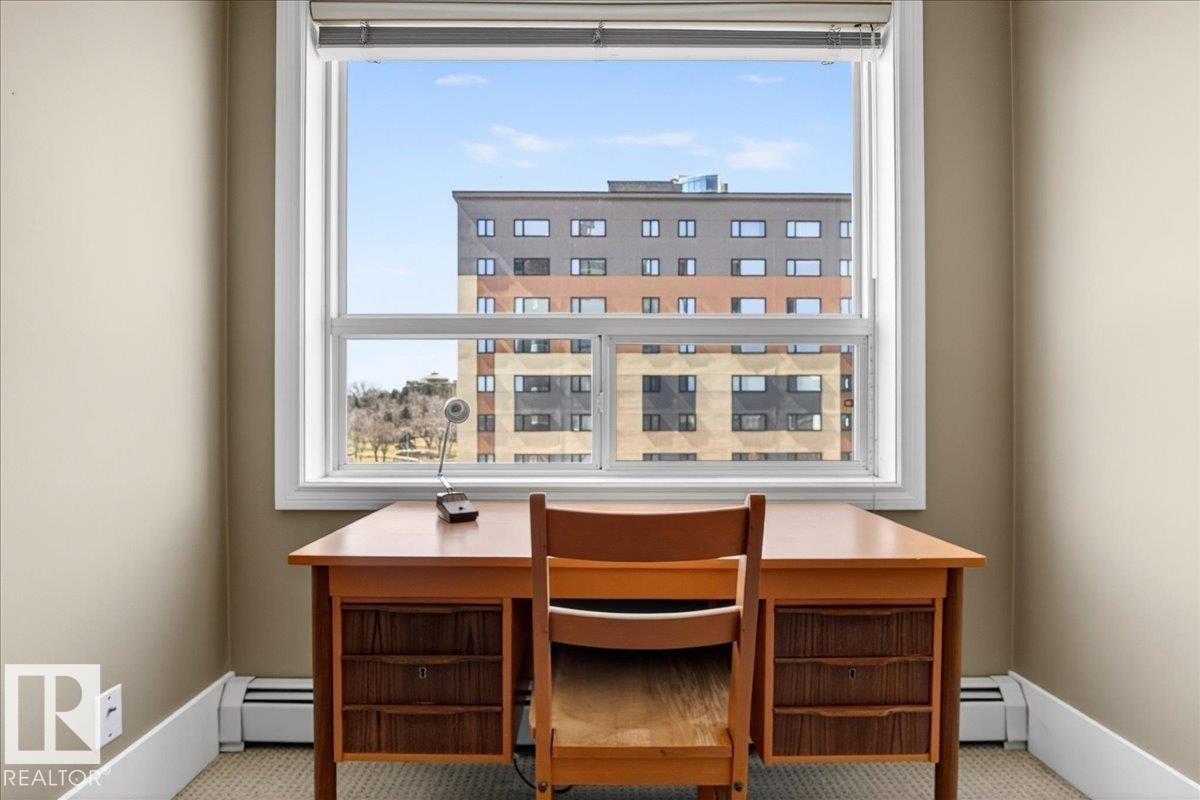 Bright room with a large window, tan painted walls, white baseboards, and carpeted flooring - 701 9707 105 Street, Edmonton, AB - Indoor Photo Showing Office