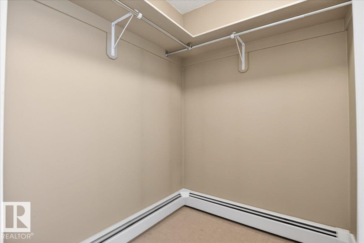 Corner closet featuring neutral-toned walls, overhead shelving, and baseboard heating - 701 9707 105 Street, Edmonton, AB - Indoor With Storage