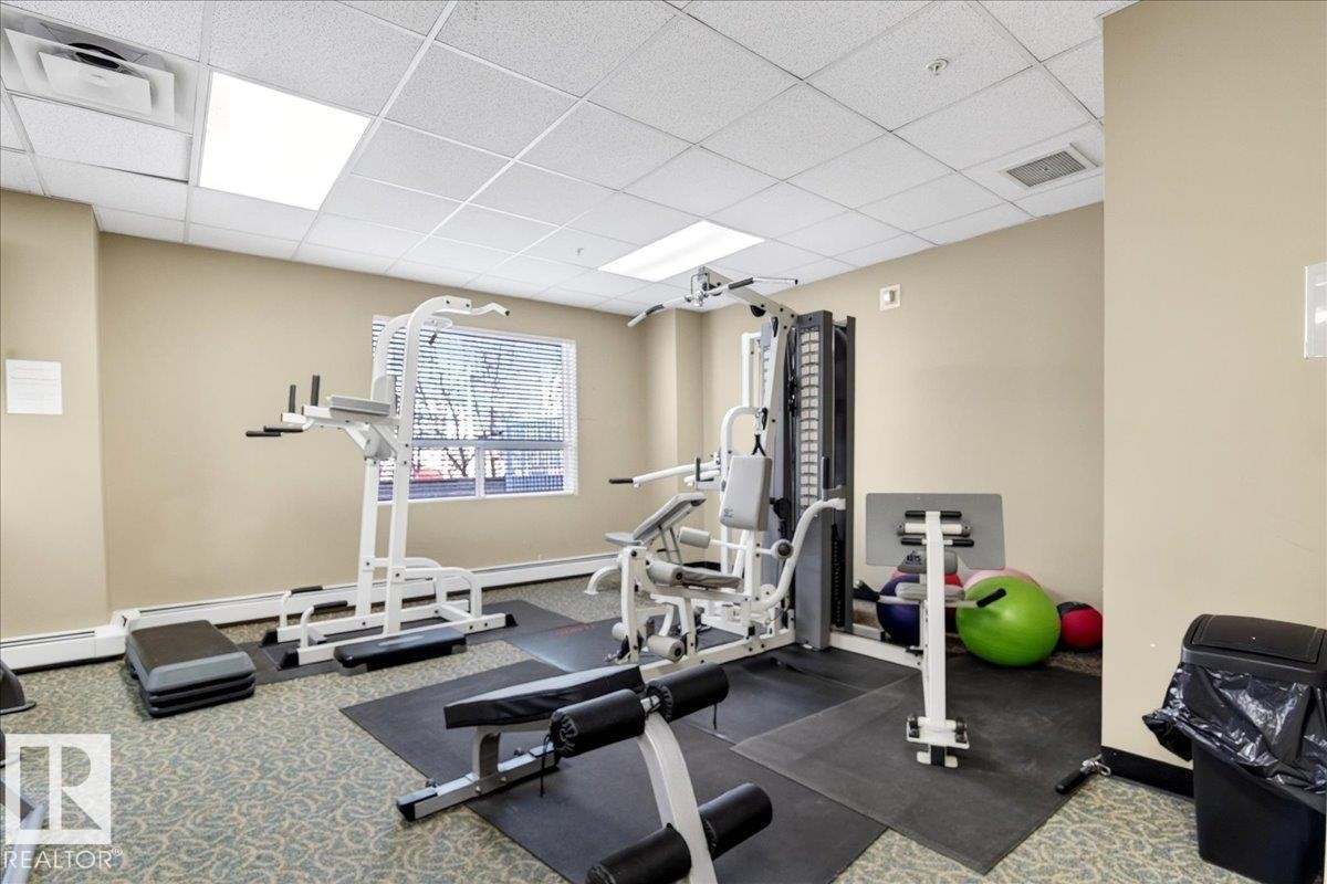 Fitness room featuring a multi-station gym, weight bench, exercise steps, and soft carpet flooring - 701 9707 105 Street, Edmonton, AB - Indoor Photo Showing Gym Room