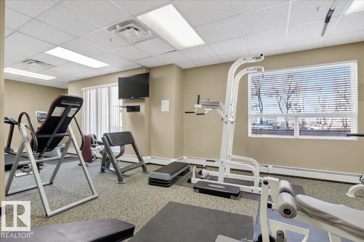 Dedicated fitness room featuring patterned carpeting and a window with blinds - 701 9707 105 Street, Edmonton, AB - Indoor Photo Showing Gym Room