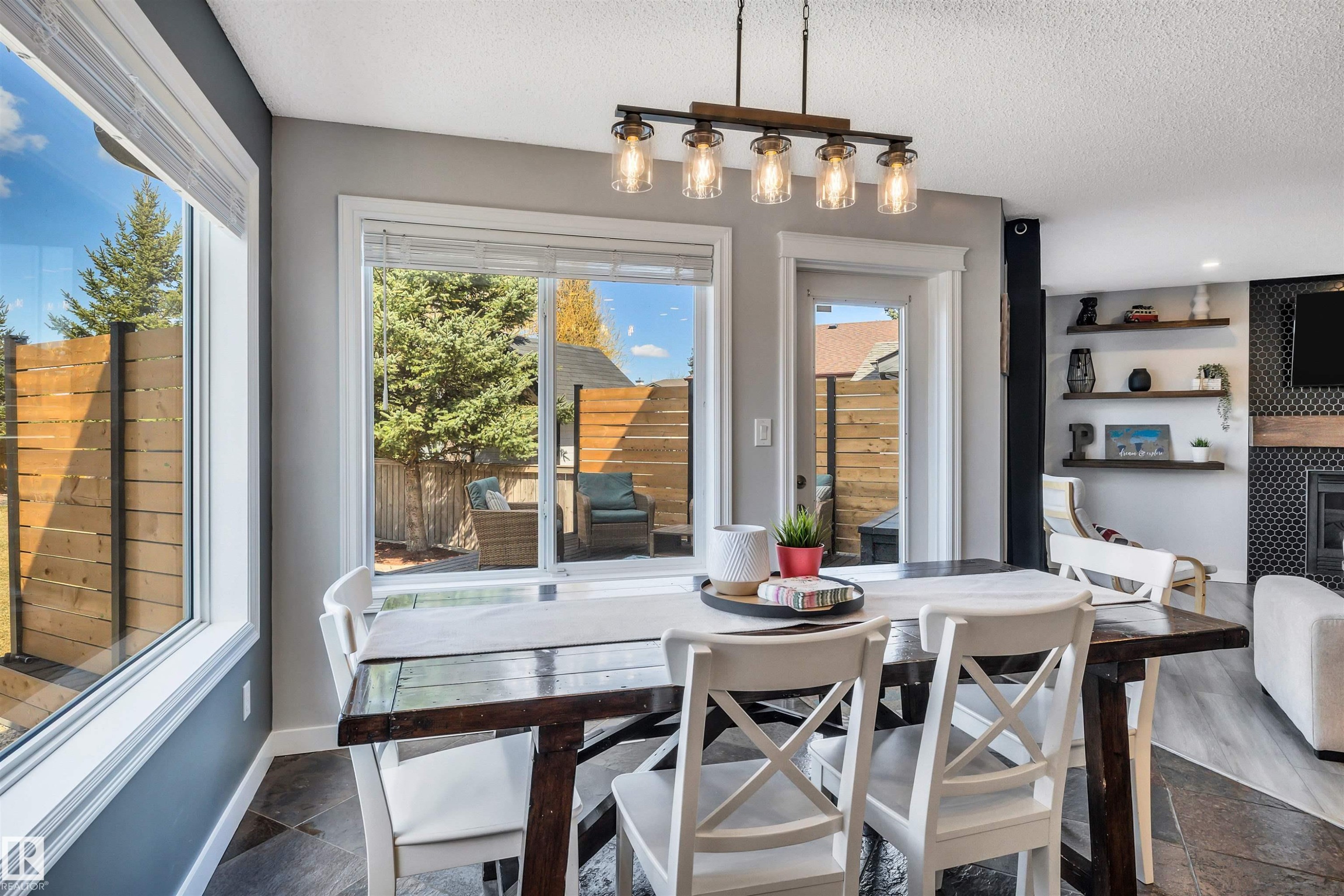 Dining area featuring a linear chandelier with glass shades, slate tile flooring, and a large picture window - 96 Bonin Crescent, Beaumont, AB - Indoor Photo Showing Dining Room
