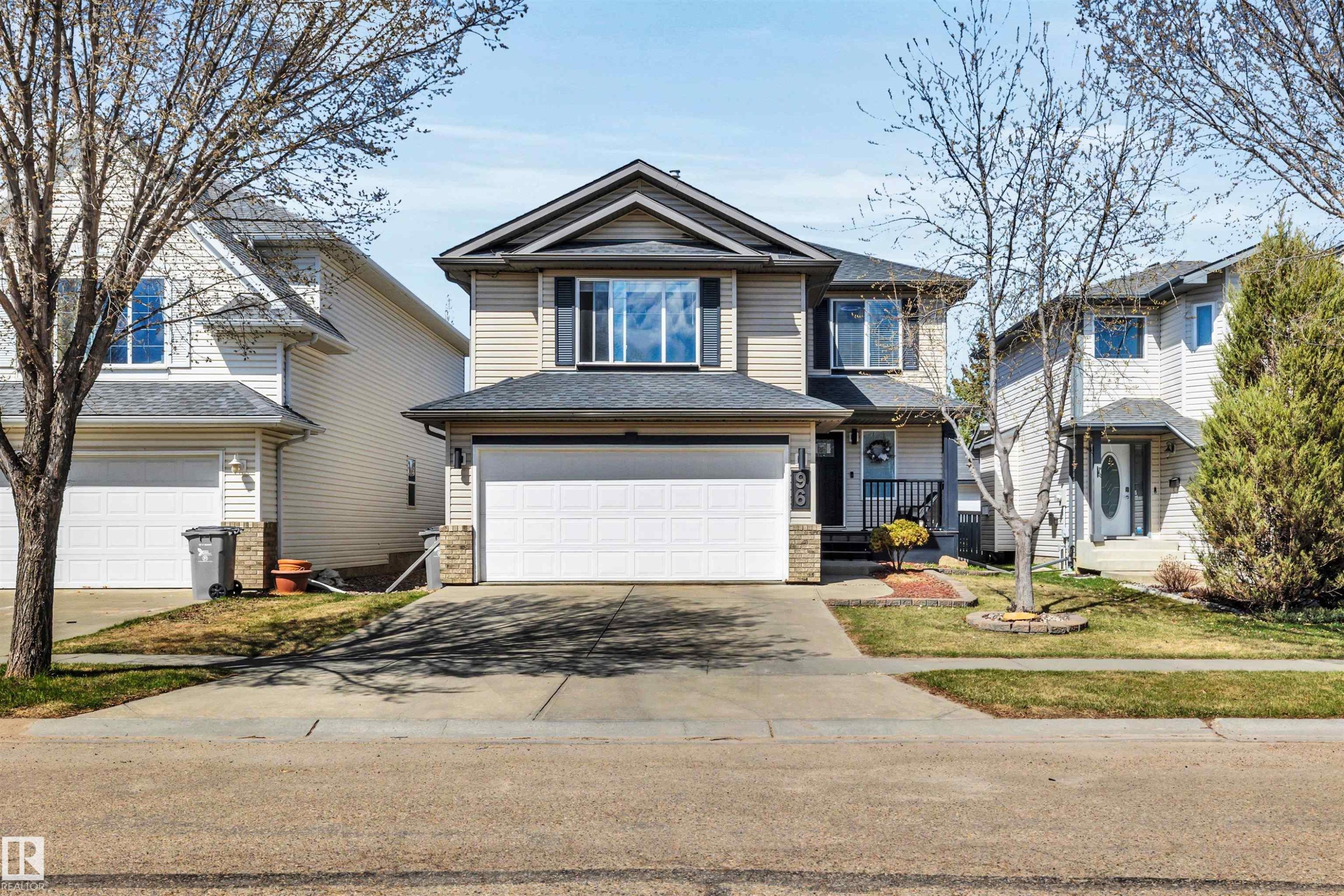 Two-story residence featuring light-toned siding, a dark shingle roof, and a prominent attached two-car garage - 96 Bonin Crescent, Beaumont, AB - Outdoor With Facade