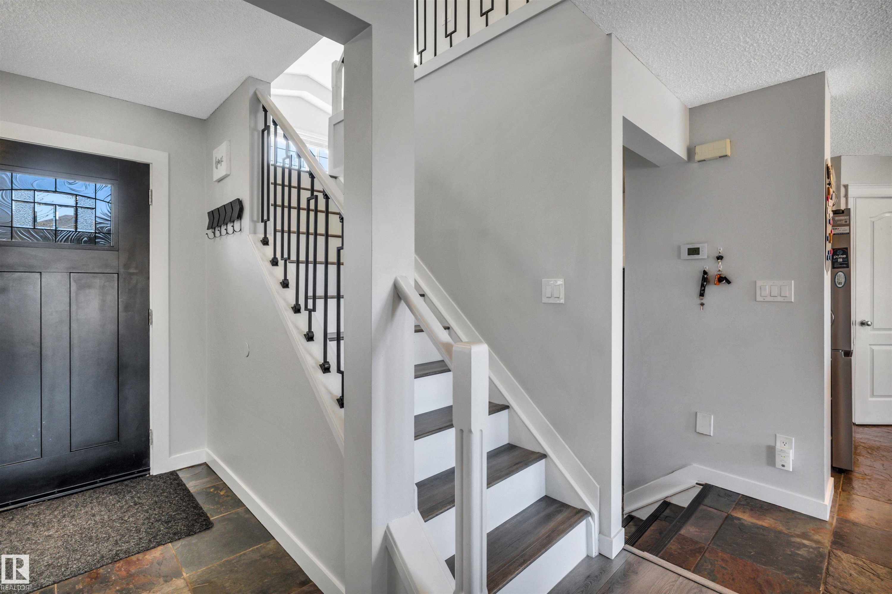 Entryway featuring slate tile flooring, a dark wood-paneled door with decorative glass inserts, and a staircase with white risers and dark wood-finish treads - 96 Bonin Crescent, Beaumont, AB - Indoor Photo Showing Other Room