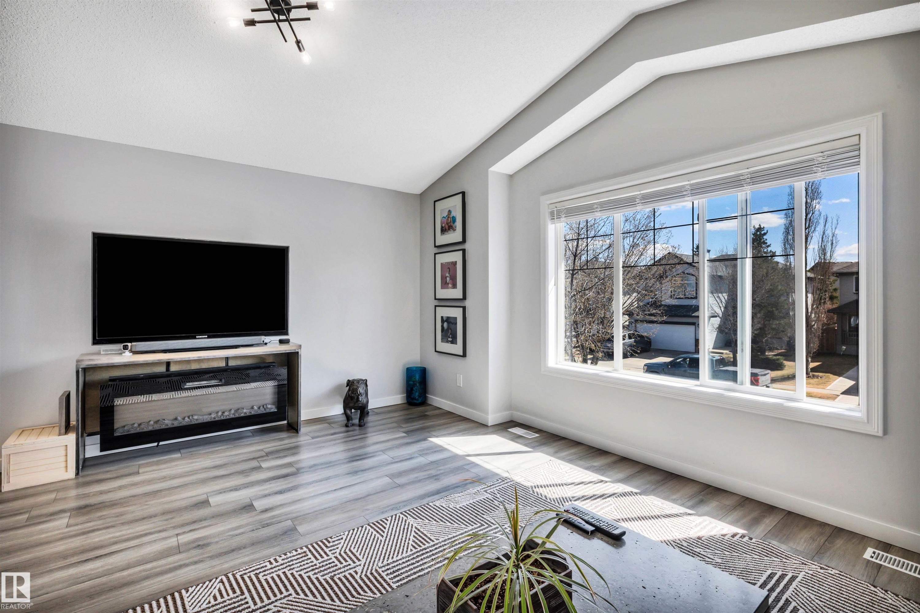 Living area featuring large multi-pane windows, vaulted ceilings, and wood-finish flooring - 96 Bonin Crescent, Beaumont, AB - Indoor Photo Showing Living Room