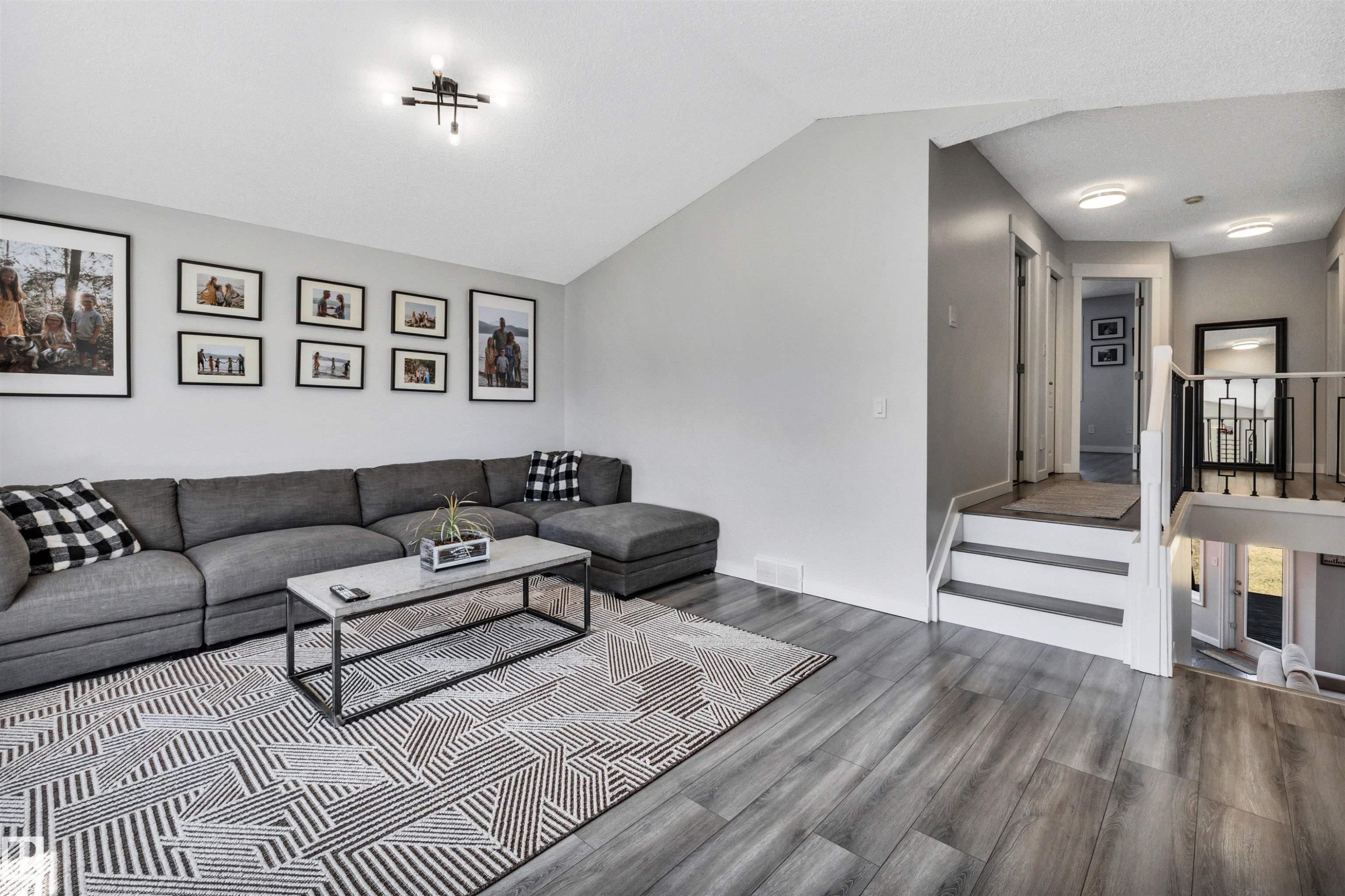 Living area featuring wood-finish flooring, vaulted ceiling, and a contemporary ceiling light fixture - 96 Bonin Crescent, Beaumont, AB - Indoor Photo Showing Living Room