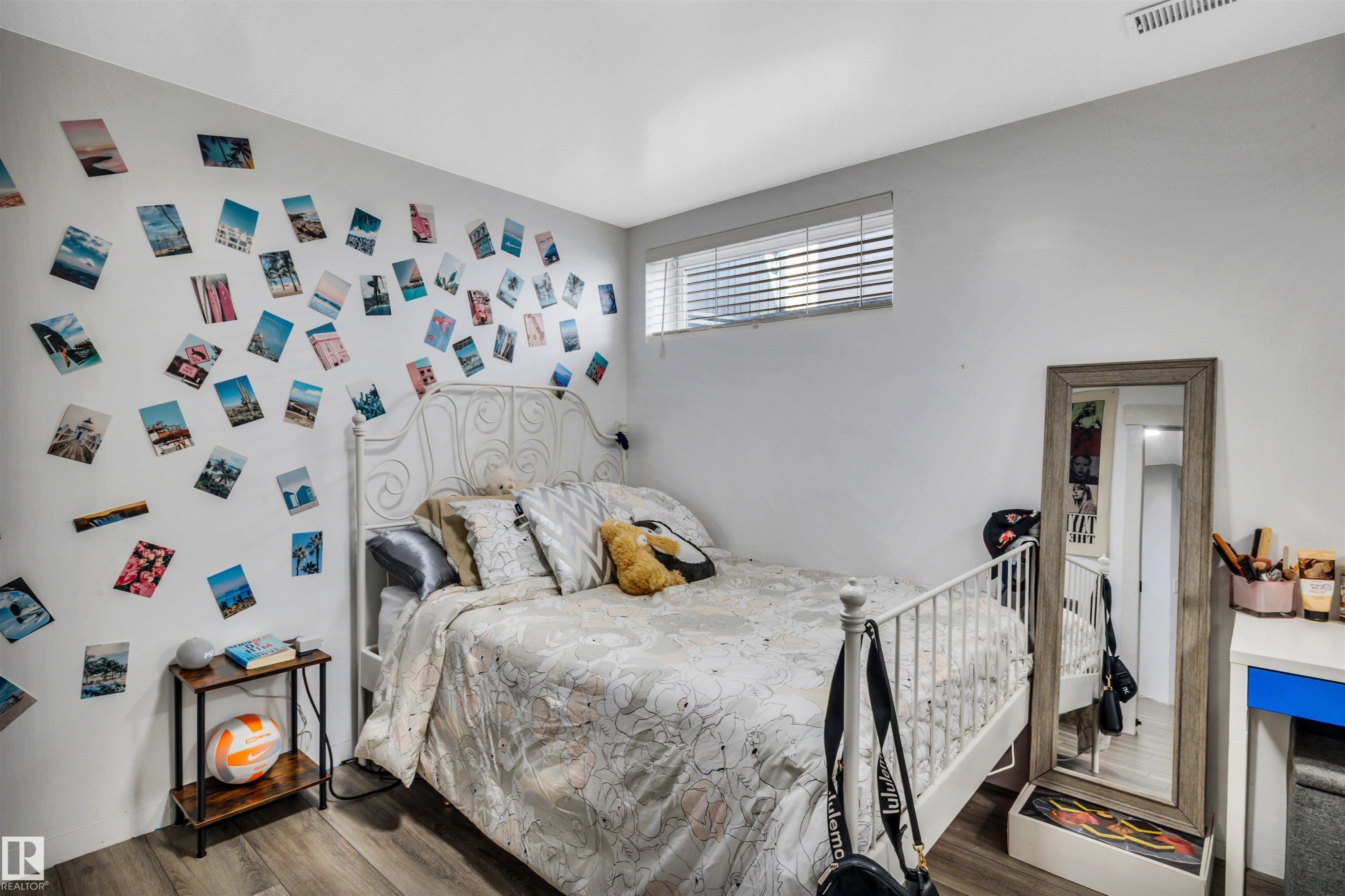 Well-lit room featuring wood-finish flooring, a white metal bed frame, and a high-set window with horizontal blinds - 96 Bonin Crescent, Beaumont, AB - Indoor Photo Showing Bedroom