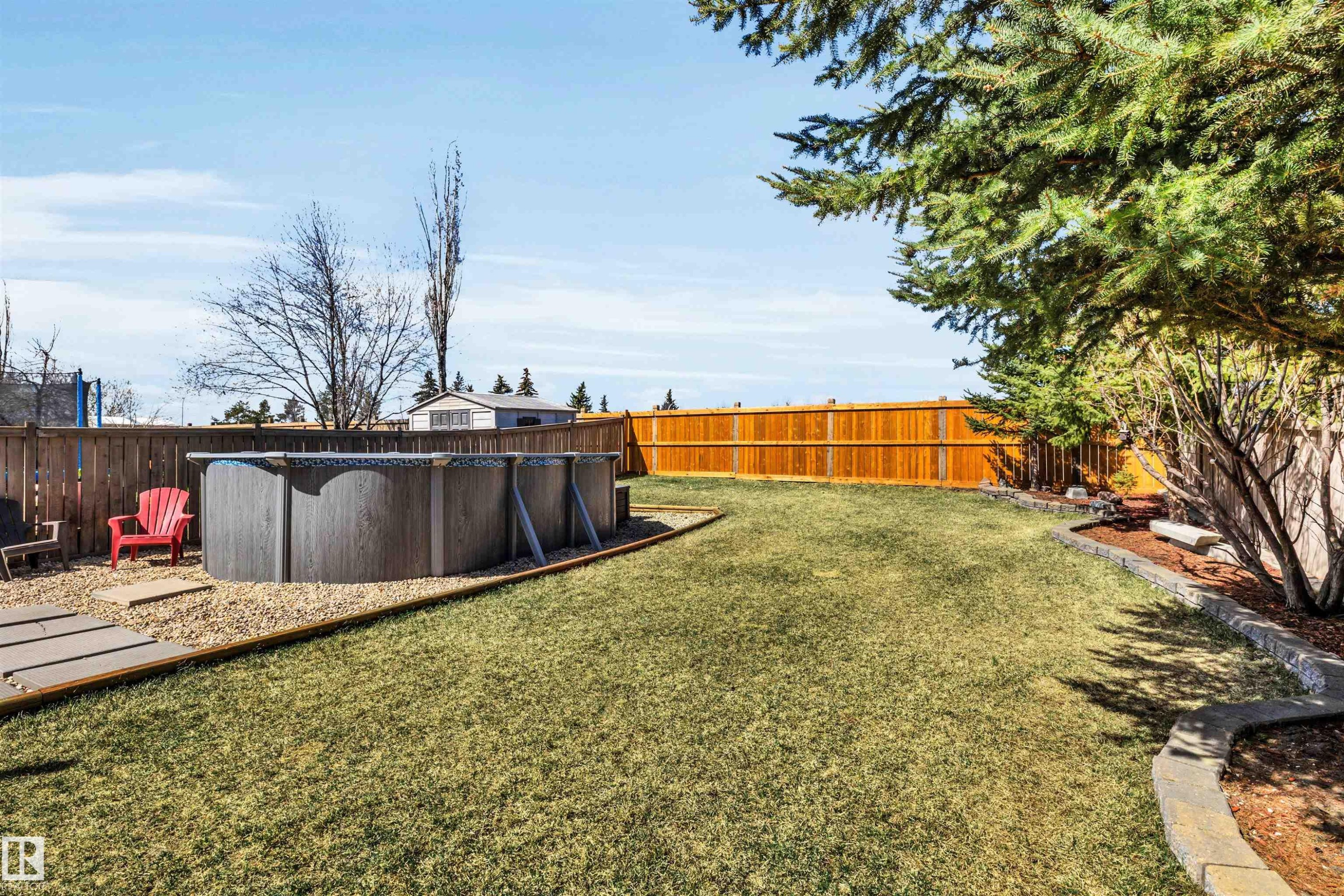 Expansive backyard featuring a manicured lawn, full privacy fencing, and mature trees - 96 Bonin Crescent, Beaumont, AB - Outdoor