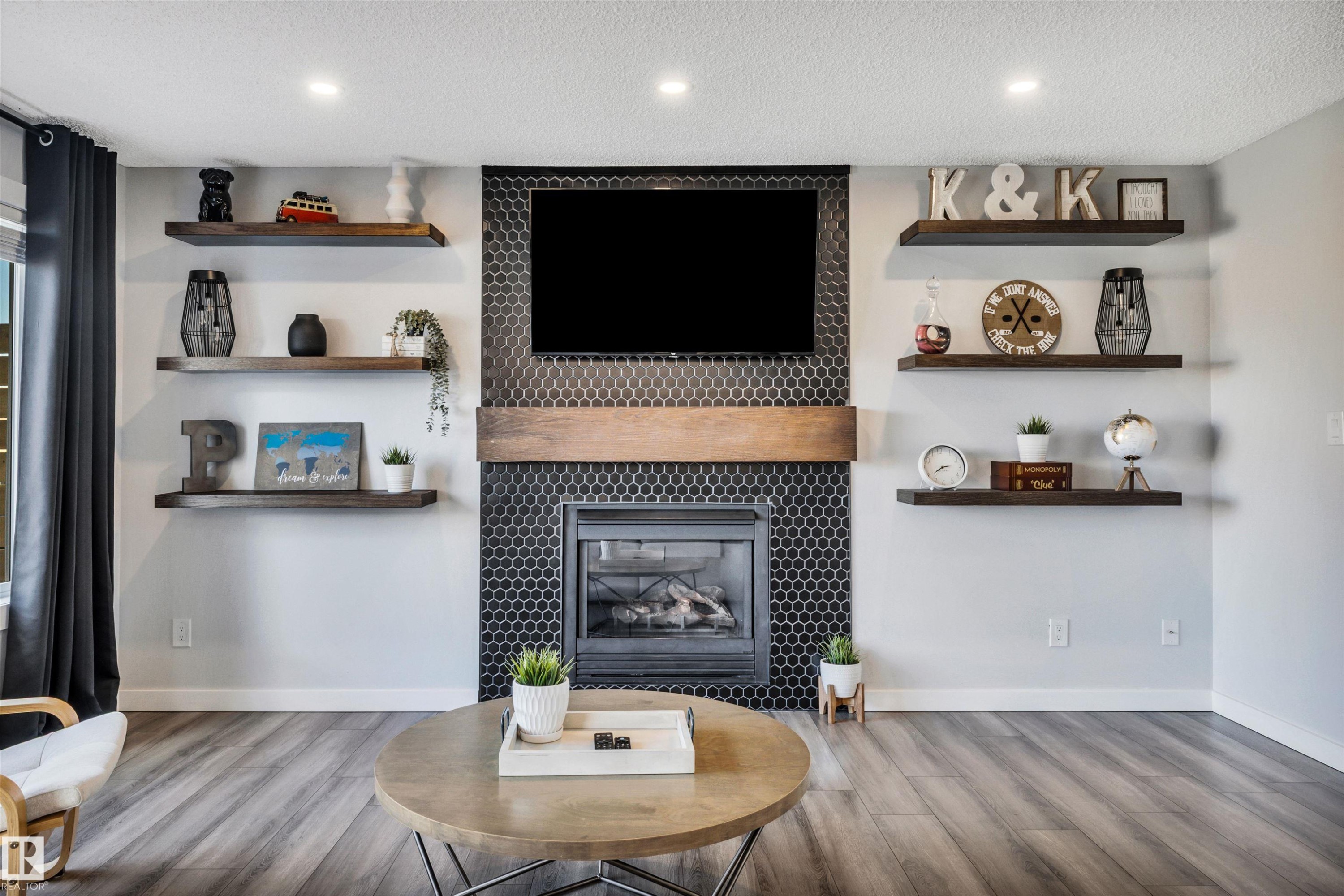 Floor-to-ceiling fireplace with black hexagonal tile surround, wood mantel, and integrated firebox - 96 Bonin Crescent, Beaumont, AB - Indoor Photo Showing Living Room With Fireplace