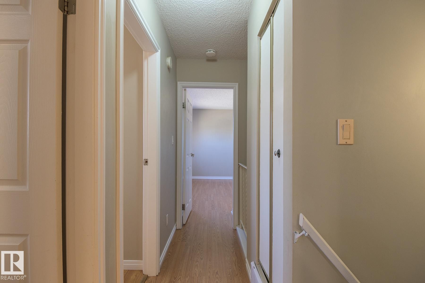 Light wood-finish flooring extending through the hallway - 8039 27 Avenue, Edmonton, AB - Indoor Photo Showing Other Room