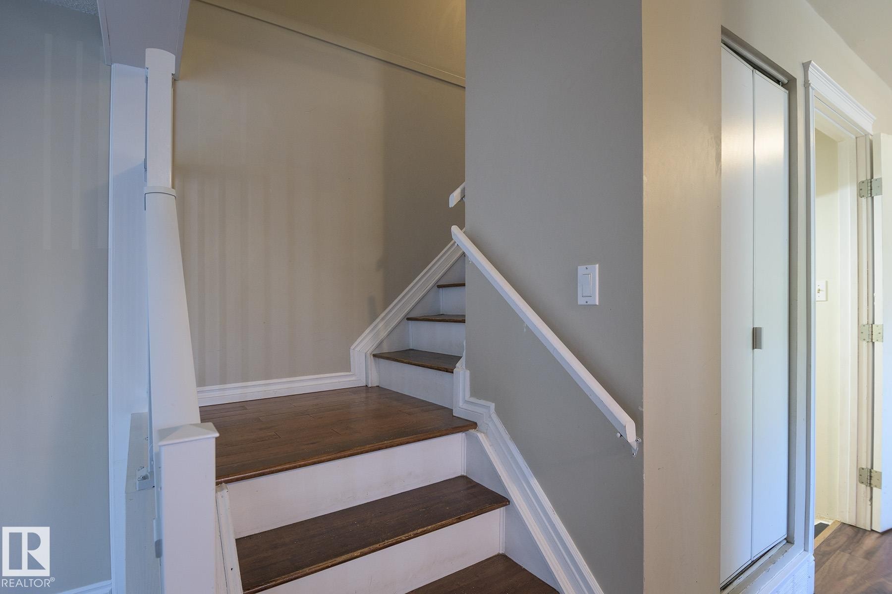 Staircase featuring wood-finish treads, painted risers, and a white handrail - 8039 27 Avenue, Edmonton, AB - Indoor Photo Showing Other Room