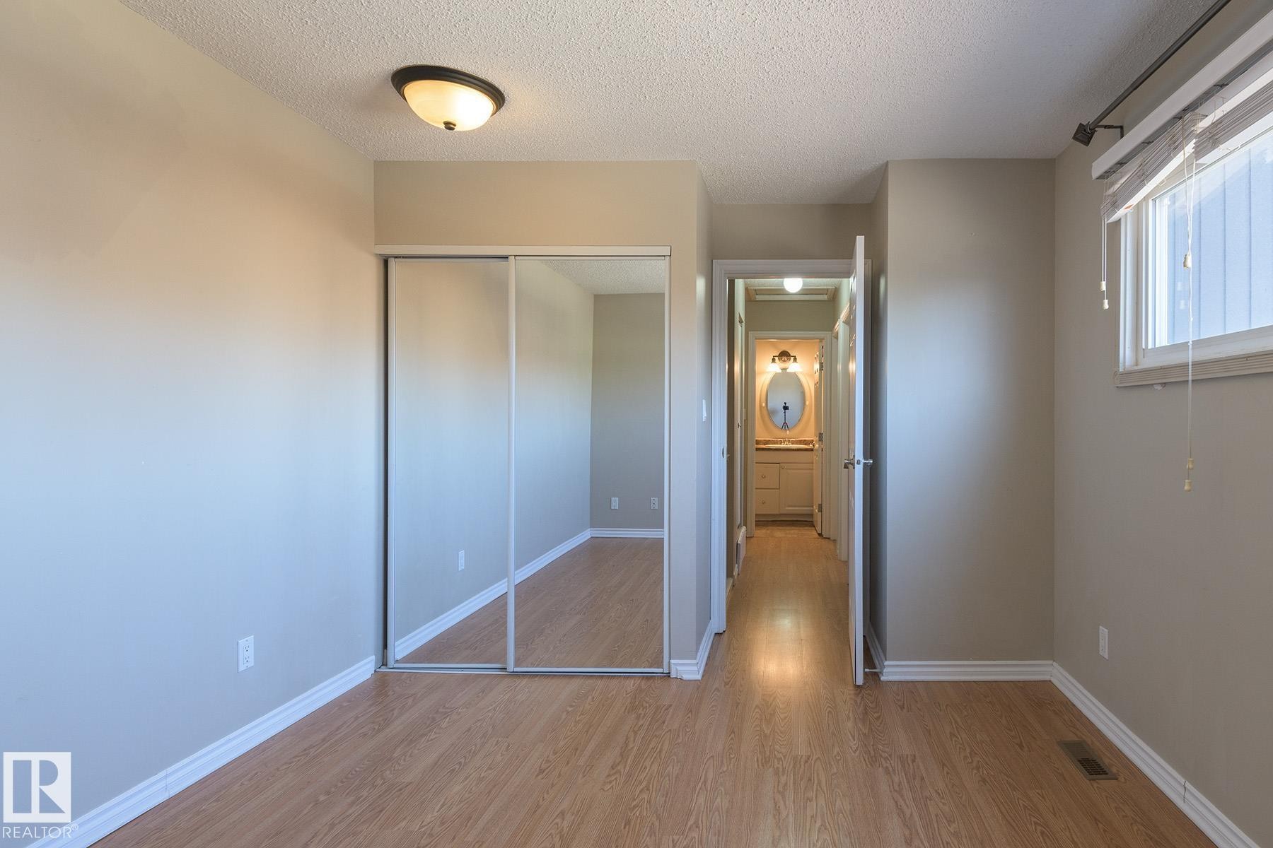 Interior room featuring wood-finish flooring, neutral wall paint, and white baseboards - 8039 27 Avenue, Edmonton, AB - Indoor Photo Showing Other Room