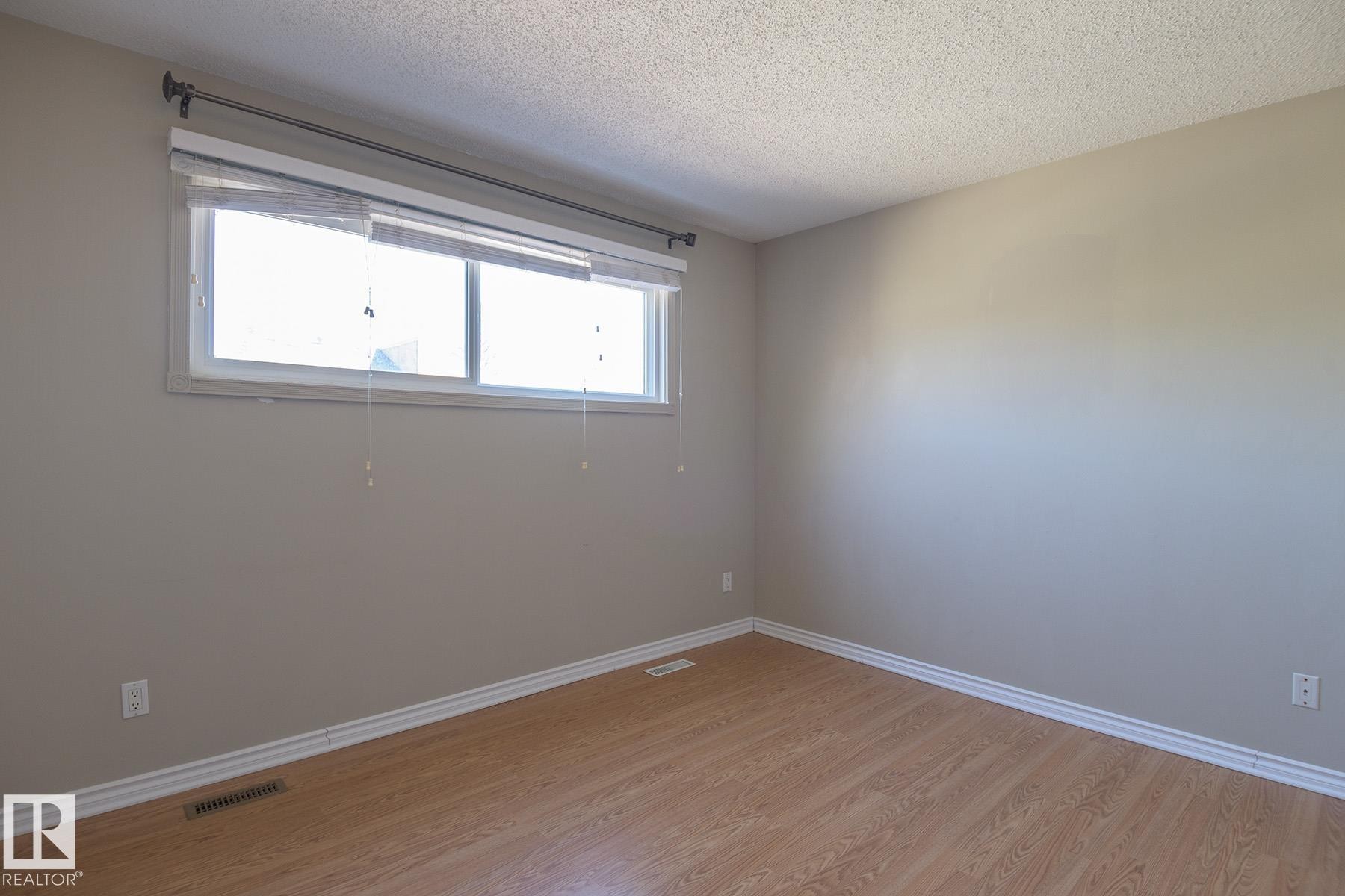 Bright interior space featuring a double window, wood-finish flooring, and neutral wall paint - 8039 27 Avenue, Edmonton, AB - Indoor Photo Showing Other Room