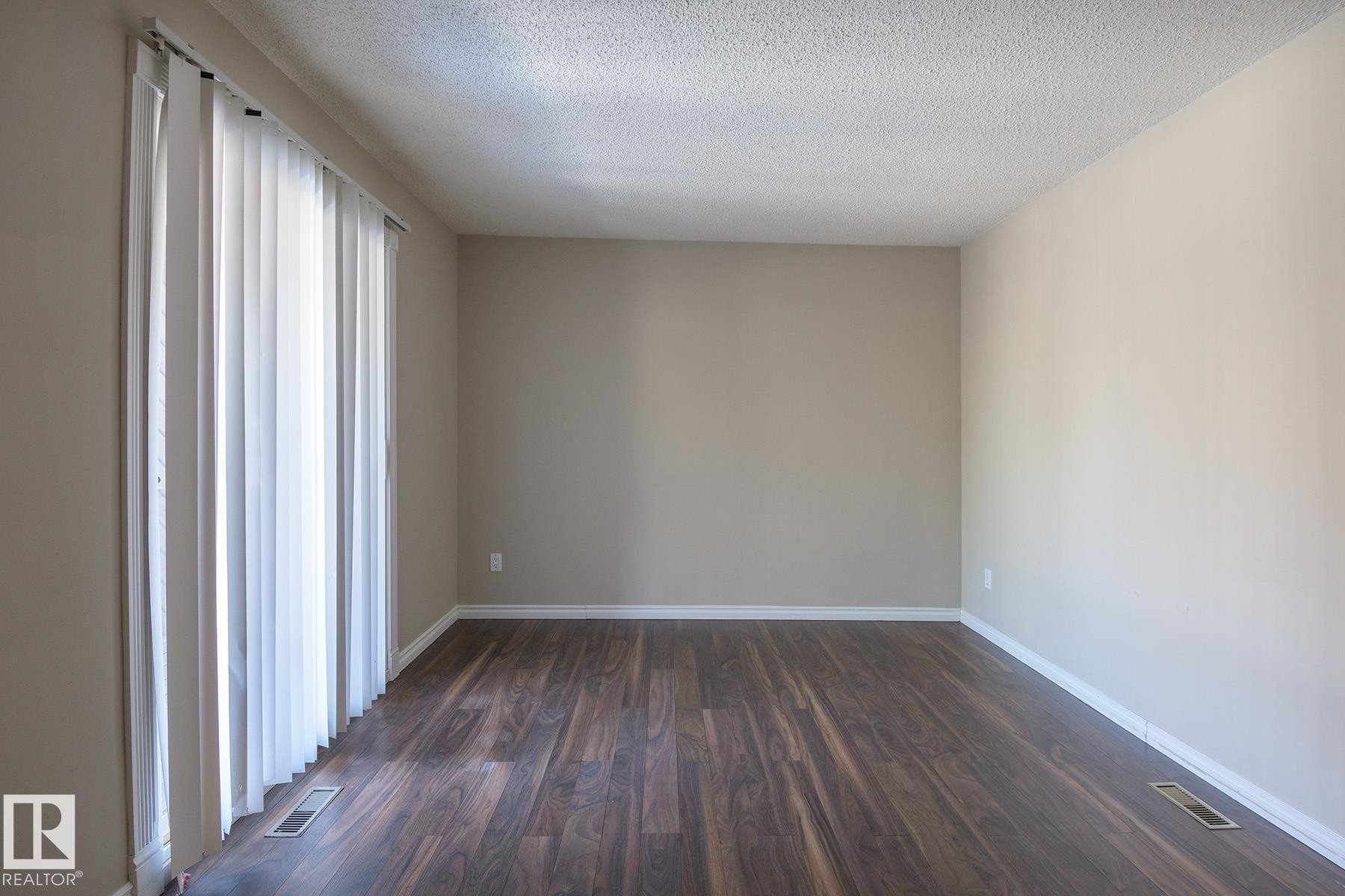 Room featuring wood-finish flooring, neutral wall tones, and white baseboards - 8039 27 Avenue, Edmonton, AB - Indoor Photo Showing Other Room