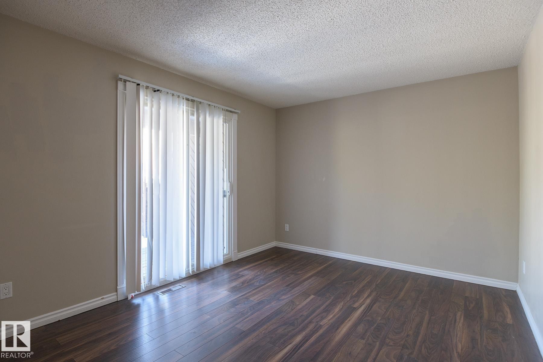 Room featuring wood-finish flooring, neutral wall tones, and white baseboards - 8039 27 Avenue, Edmonton, AB - Indoor Photo Showing Other Room