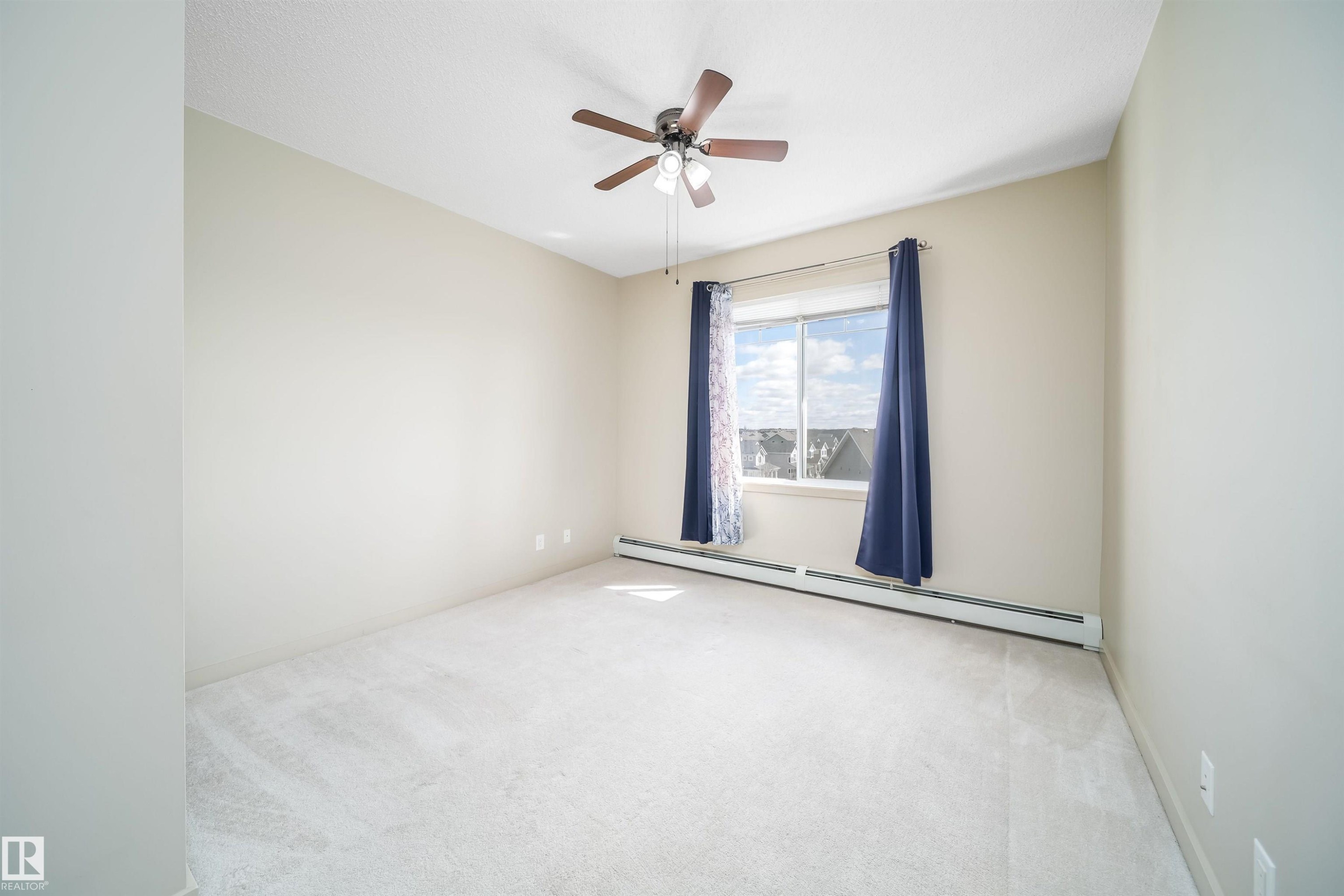Light-colored carpeting and neutral wall tones create an open atmosphere - 421 4008 Savaryn Drive, Edmonton, AB - Indoor Photo Showing Other Room