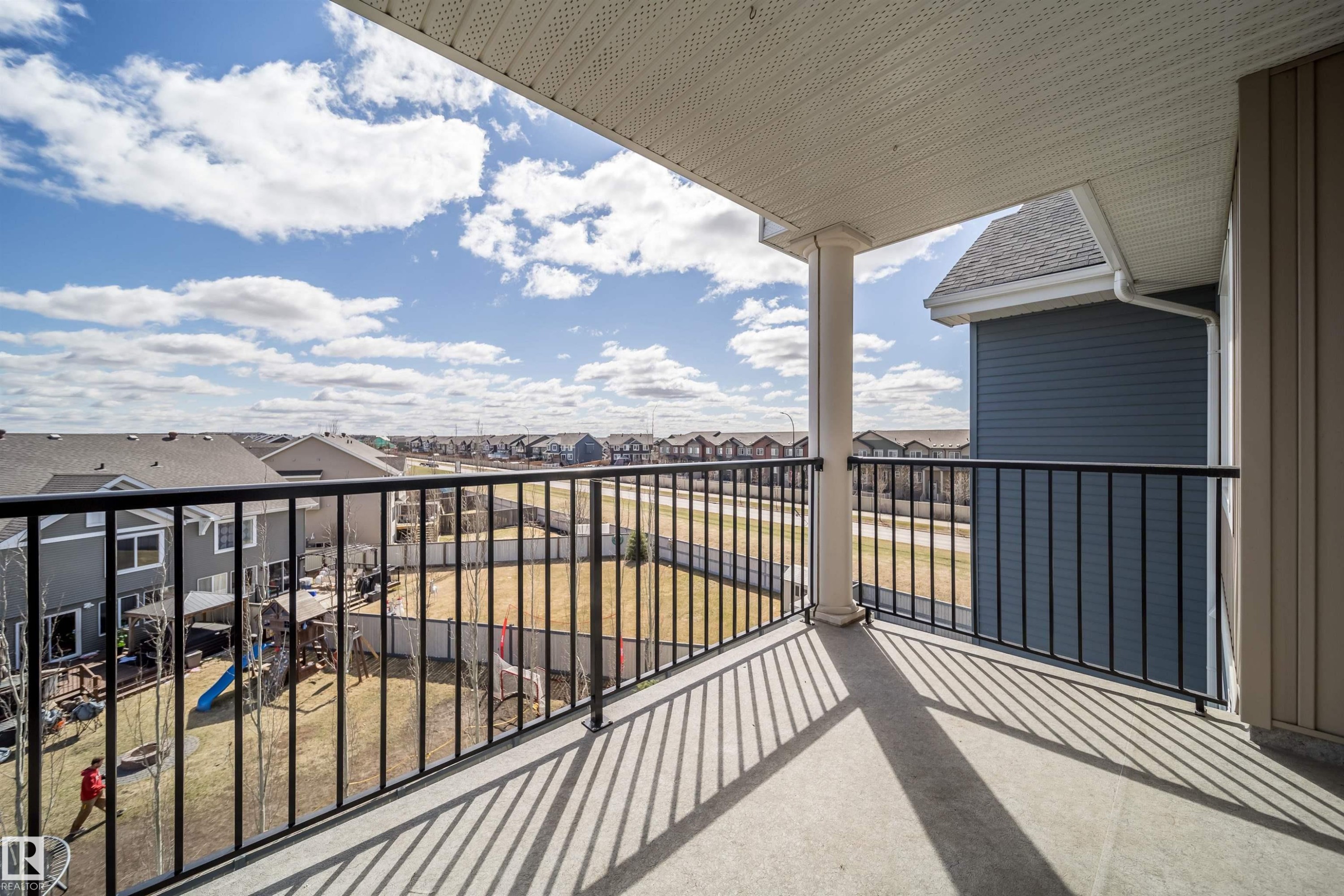 Exterior balcony featuring a concrete floor, black metal railings, a white support column, and a textured white soffit ceiling - 421 4008 Savaryn Drive, Edmonton, AB - Outdoor With Exterior