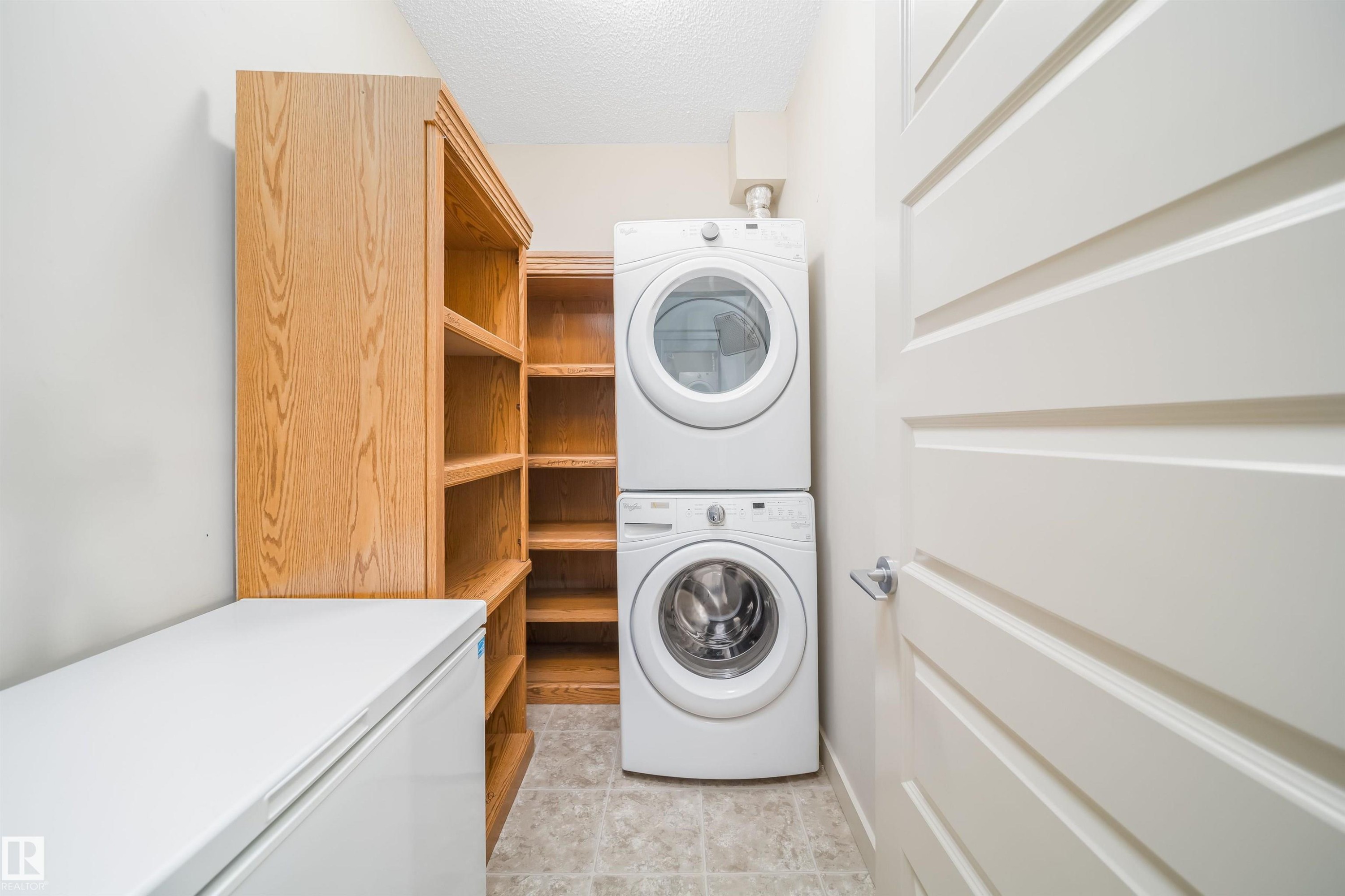 Dedicated laundry space featuring a stacked washer and dryer unit - 421 4008 Savaryn Drive, Edmonton, AB - Indoor Photo Showing Laundry Room