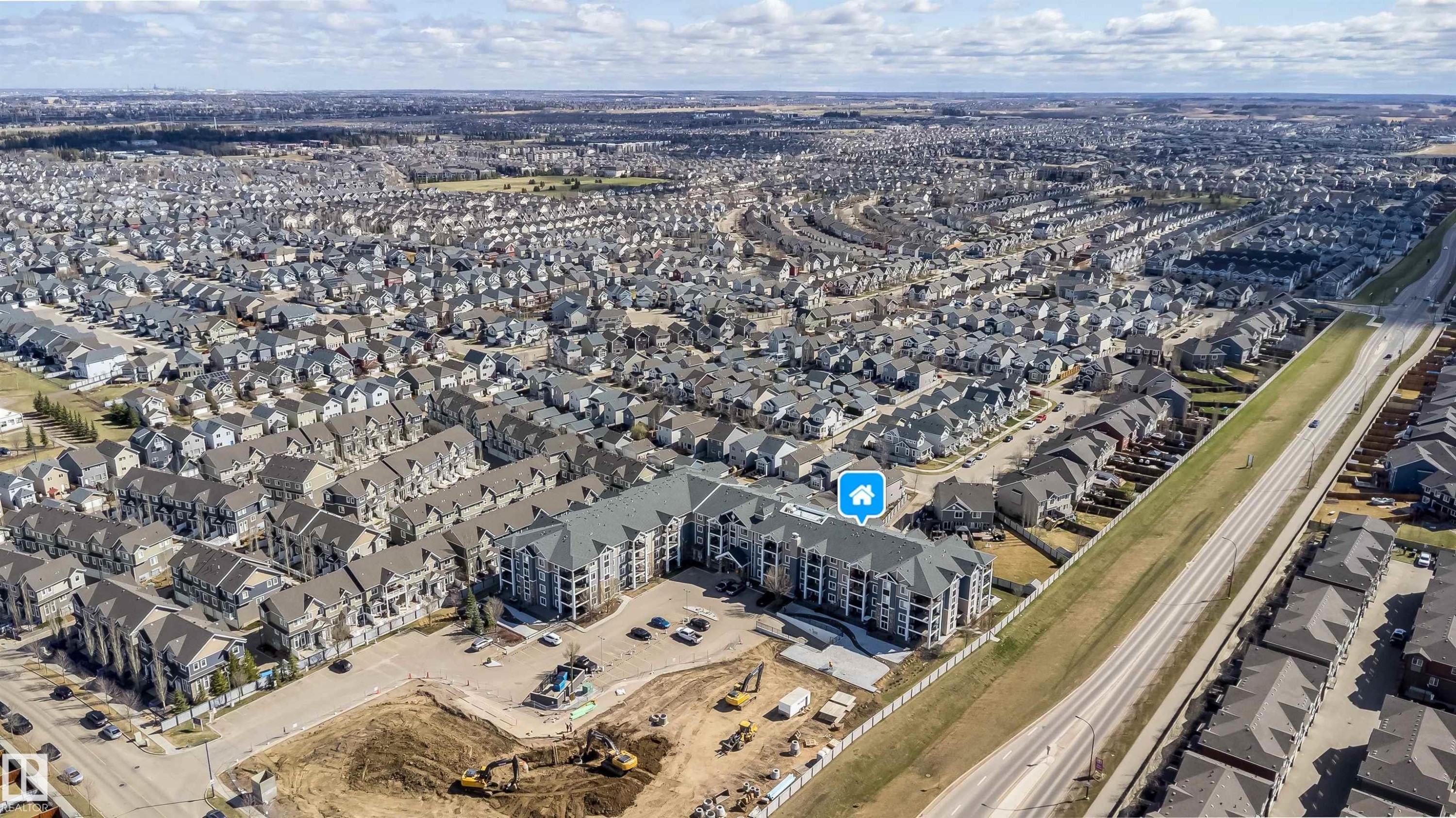Expansive aerial view showcasing a large residential community featuring a multi-story condominium building with multiple balconies - 421 4008 Savaryn Drive, Edmonton, AB - Outdoor With View