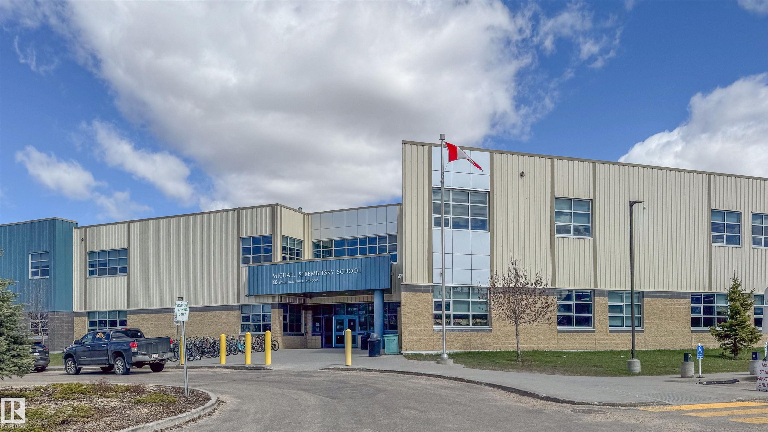 Modern institutional building with a prominent entrance canopy, featuring a brick base and metal panel siding - 421 4008 Savaryn Drive, Edmonton, AB - Outdoor