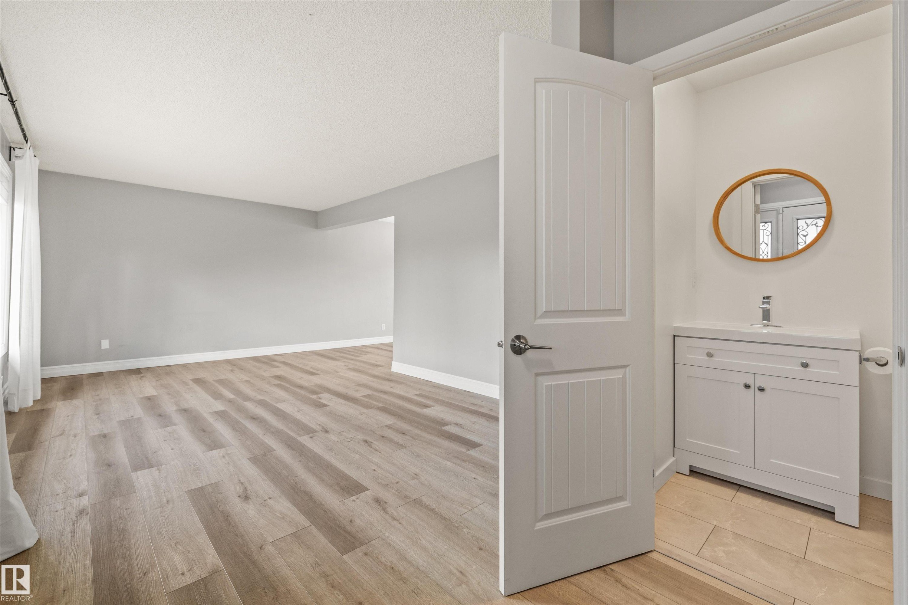 Spacious interior with wood-finish flooring and light gray painted walls - 7927 71 Avenue, Edmonton, AB - Indoor Photo Showing Other Room