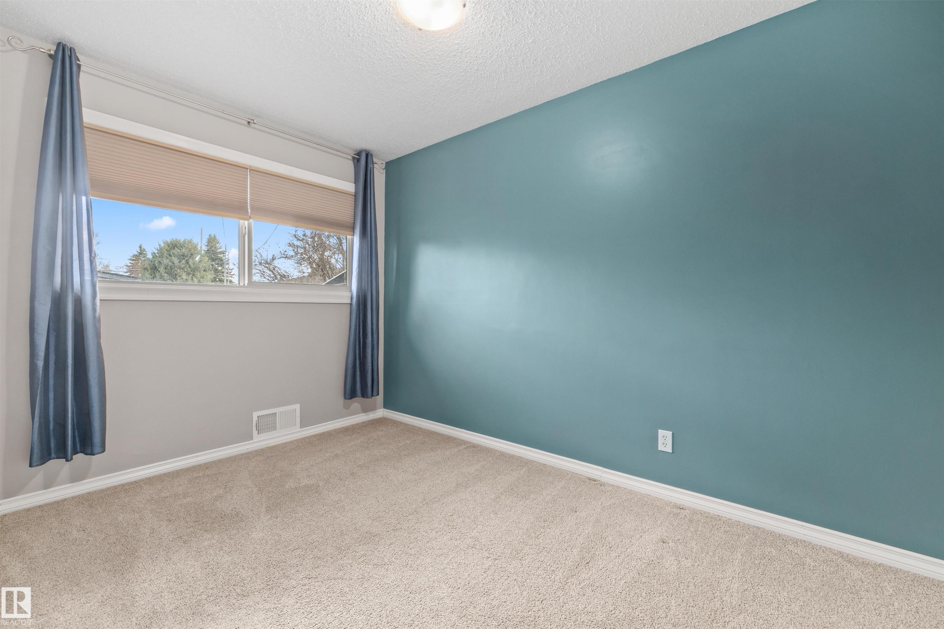 Carpeted room featuring a light beige color palette, a window with cellular shades, and a ceiling-mounted light fixture - 7927 71 Avenue, Edmonton, AB - Indoor Photo Showing Other Room