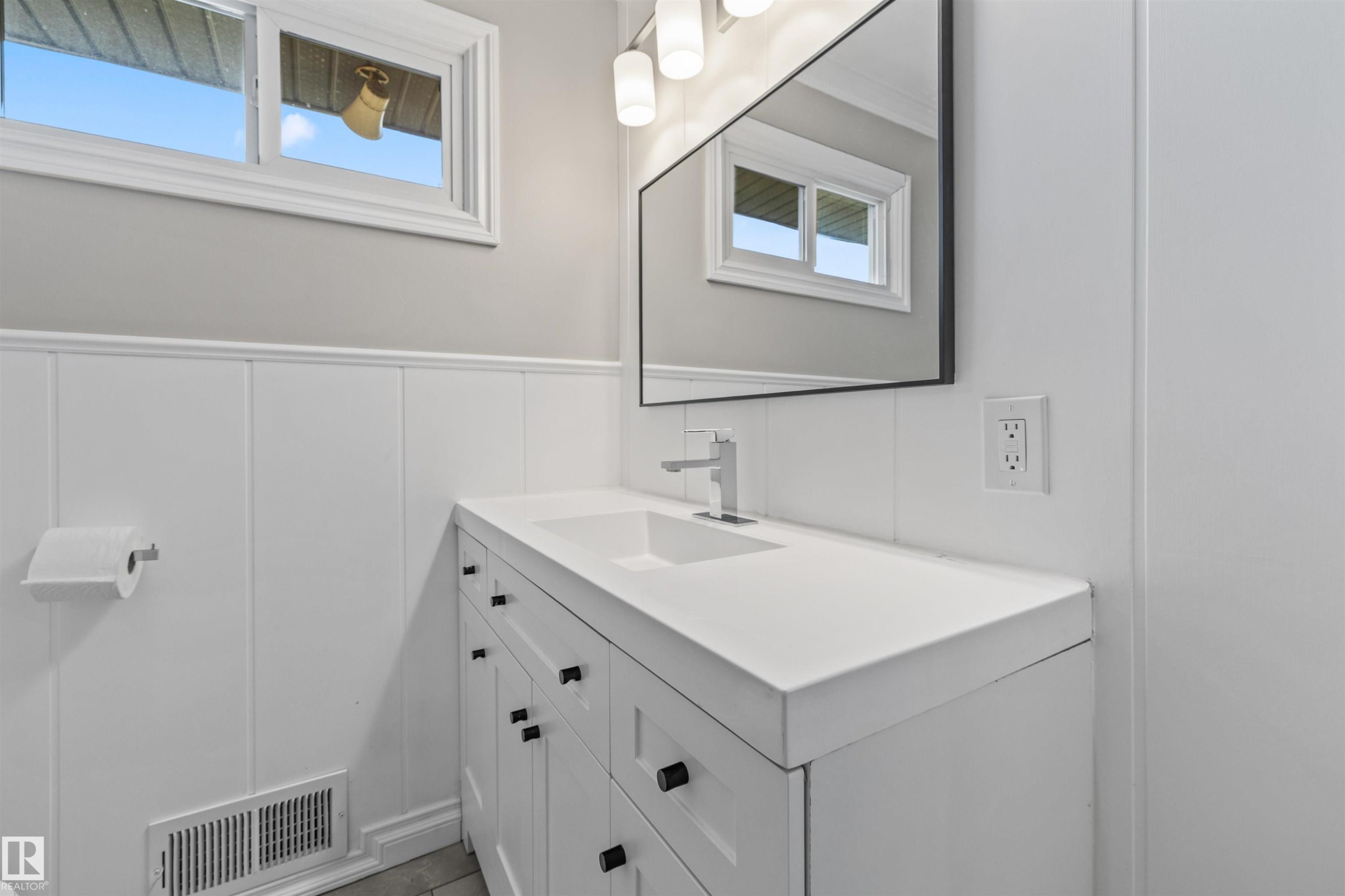 Bathroom featuring a white vanity with integrated sink, chrome faucet, and matte black hardware - 7927 71 Avenue, Edmonton, AB - Indoor Photo Showing Bathroom