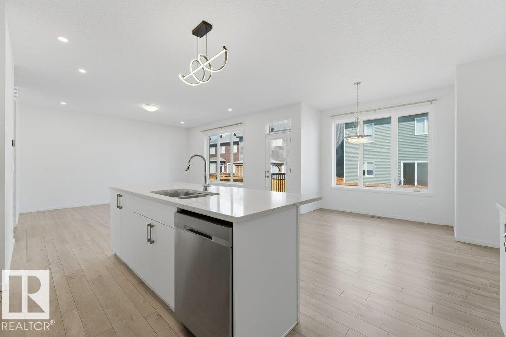 Open-concept living area featuring light wood-finish flooring, white walls, and recessed lighting - 2011 207 Street, Edmonton, AB - Indoor Photo Showing Kitchen With Double Sink