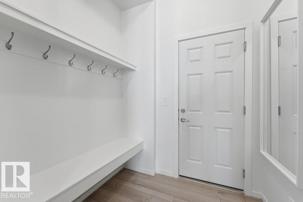 Entryway featuring white six-panel door, built-in storage bench, and wall-mounted coat hooks - 2011 207 Street, Edmonton, AB - Indoor Photo Showing Other Room