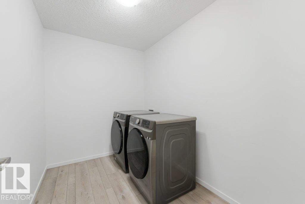 Dedicated laundry space featuring wood-finish flooring, white walls, and a ceiling-mounted light fixture - 2011 207 Street, Edmonton, AB - Indoor Photo Showing Laundry Room