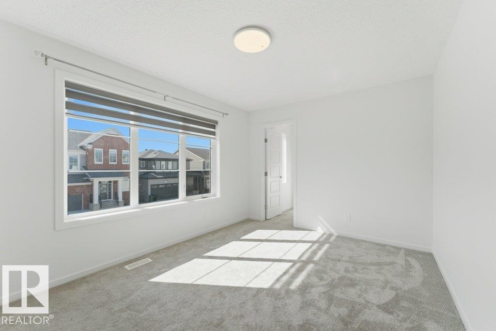 Bright room featuring a large window with horizontal blinds, neutral wall paint, and gray carpet flooring - 2011 207 Street, Edmonton, AB - Indoor Photo Showing Other Room