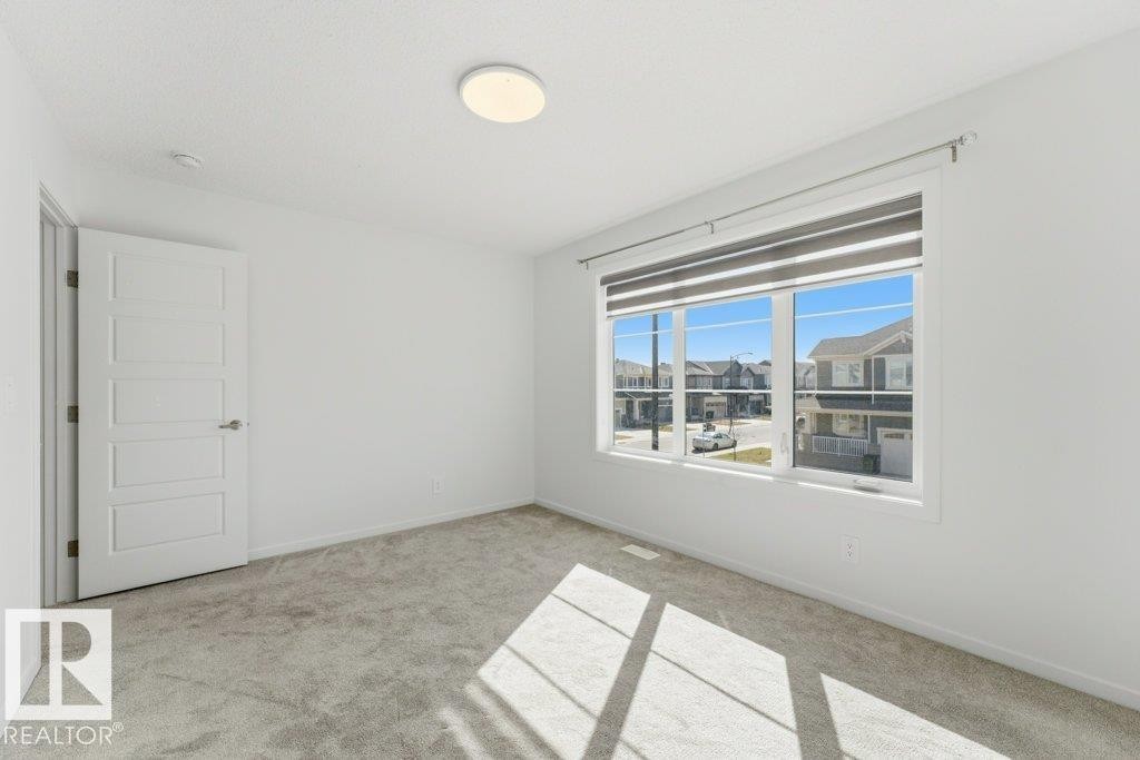 Neutral-toned carpeting and white walls define this room, featuring a large window with roller shades - 2011 207 Street, Edmonton, AB - Indoor Photo Showing Other Room