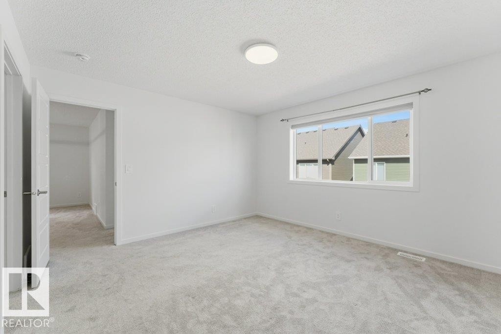 Carpeted room featuring a large window, a flush-mount ceiling light, and a dedicated closet space - 2011 207 Street, Edmonton, AB - Indoor Photo Showing Other Room