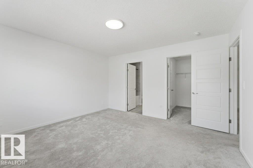 Spacious room featuring light gray carpet flooring, white walls, and a round flush-mount ceiling light - 2011 207 Street, Edmonton, AB - Indoor Photo Showing Other Room