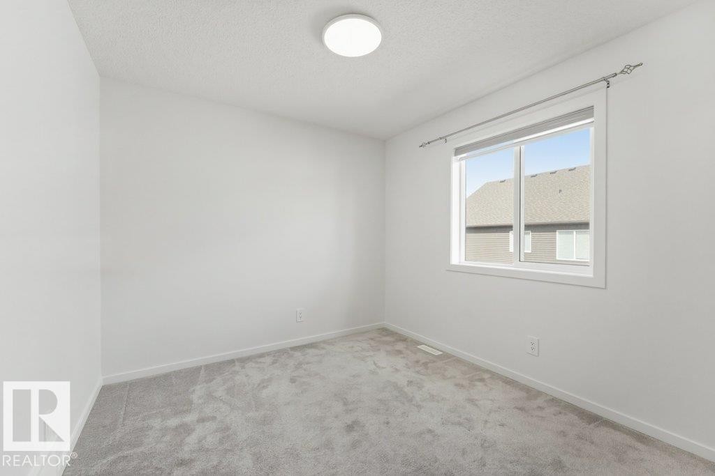Neutral-toned room featuring a large window, light-colored walls, and gray carpeting - 2011 207 Street, Edmonton, AB - Indoor Photo Showing Other Room