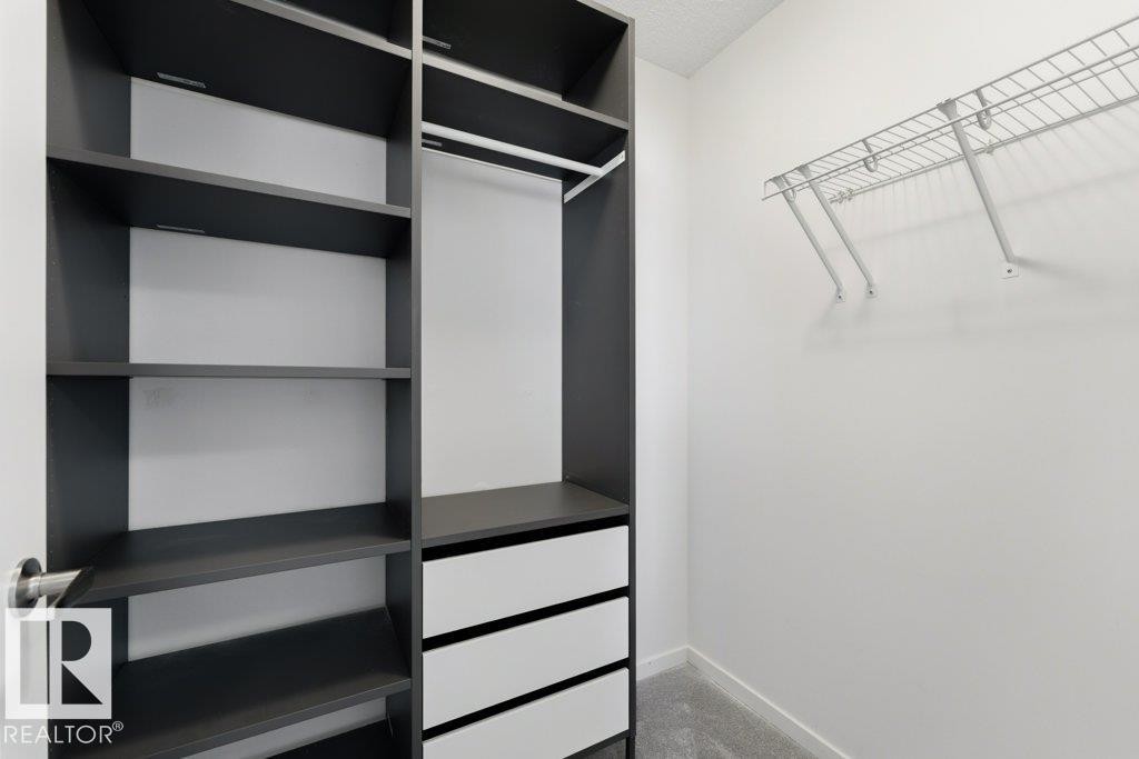 Custom closet system featuring dark wood-finish shelving, built-in drawers, and an integrated hanging rod - 2011 207 Street, Edmonton, AB - Indoor With Storage