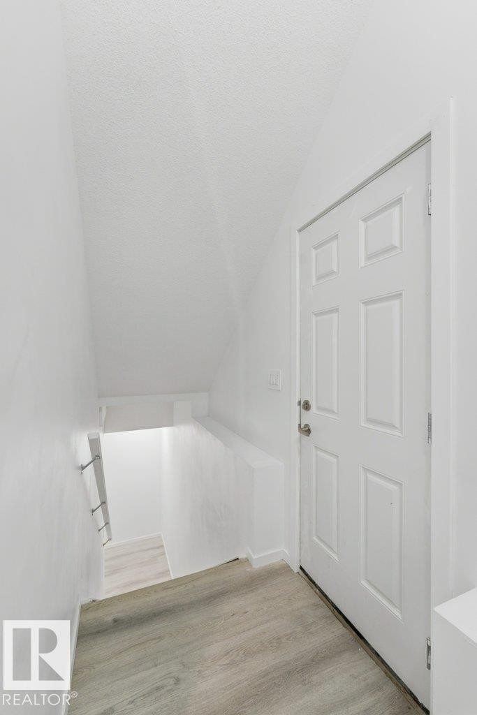 Entryway featuring wood-finish flooring, a six-panel door with silver hardware, and painted white walls - 2011 207 Street, Edmonton, AB - Indoor Photo Showing Other Room
