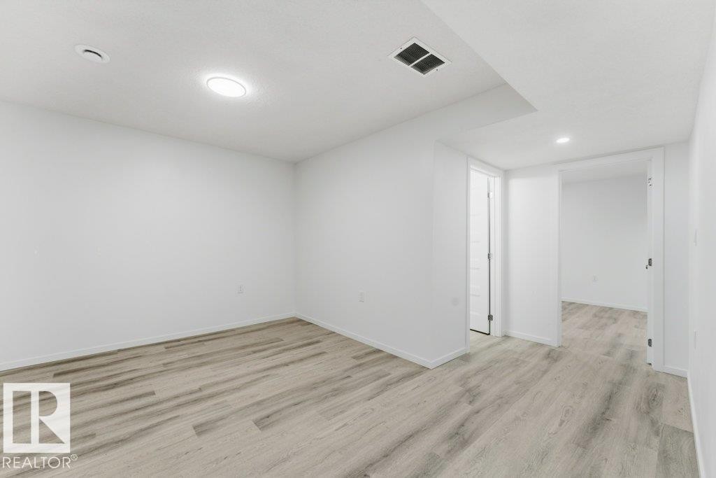 Spacious room featuring light wood-finish flooring, recessed lighting, white walls, and white trim - 2011 207 Street, Edmonton, AB - Indoor Photo Showing Other Room