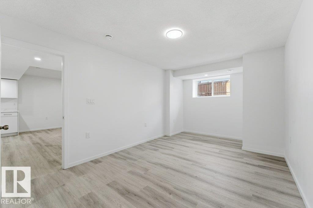 Open concept room featuring wood-finish flooring, recessed lighting, and a window - 2011 207 Street, Edmonton, AB - Indoor Photo Showing Other Room