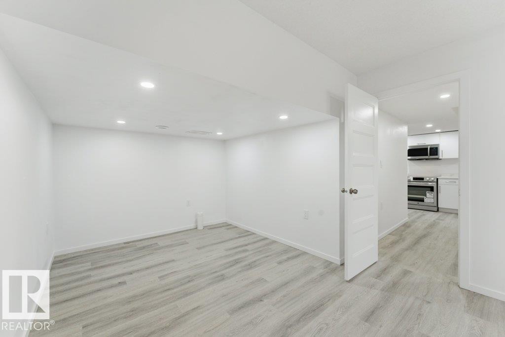 Spacious room featuring light wood-finish flooring, recessed lighting, and a crisp white color palette - 2011 207 Street, Edmonton, AB - Indoor Photo Showing Other Room