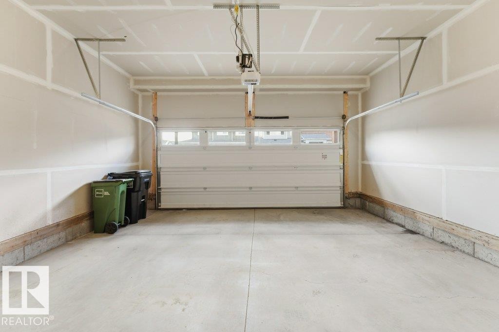 Spacious garage featuring a concrete floor, painted drywall, and an overhead garage door with integrated windows - 2011 207 Street, Edmonton, AB - Indoor Photo Showing Garage