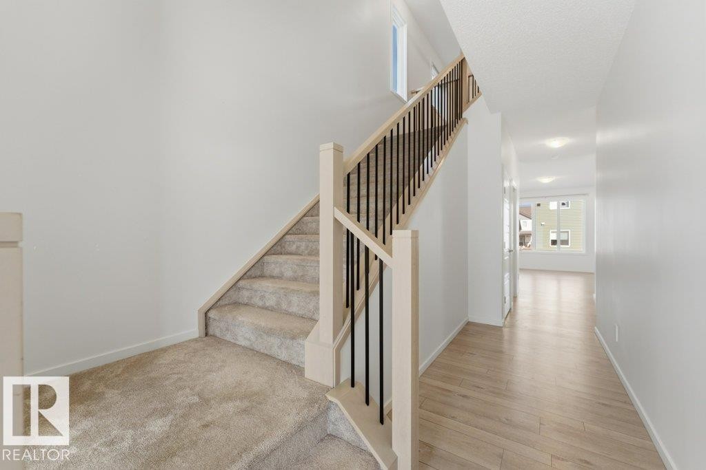 Staircase featuring light wood newel posts, black metal spindles, and carpeted treads - 2011 207 Street, Edmonton, AB - Indoor Photo Showing Other Room