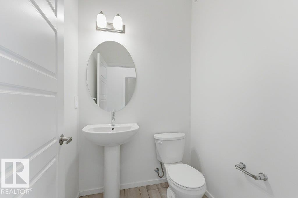 Bathroom featuring a pedestal sink, oval mirror, and wall-mounted light fixture - 2011 207 Street, Edmonton, AB - Indoor Photo Showing Bathroom