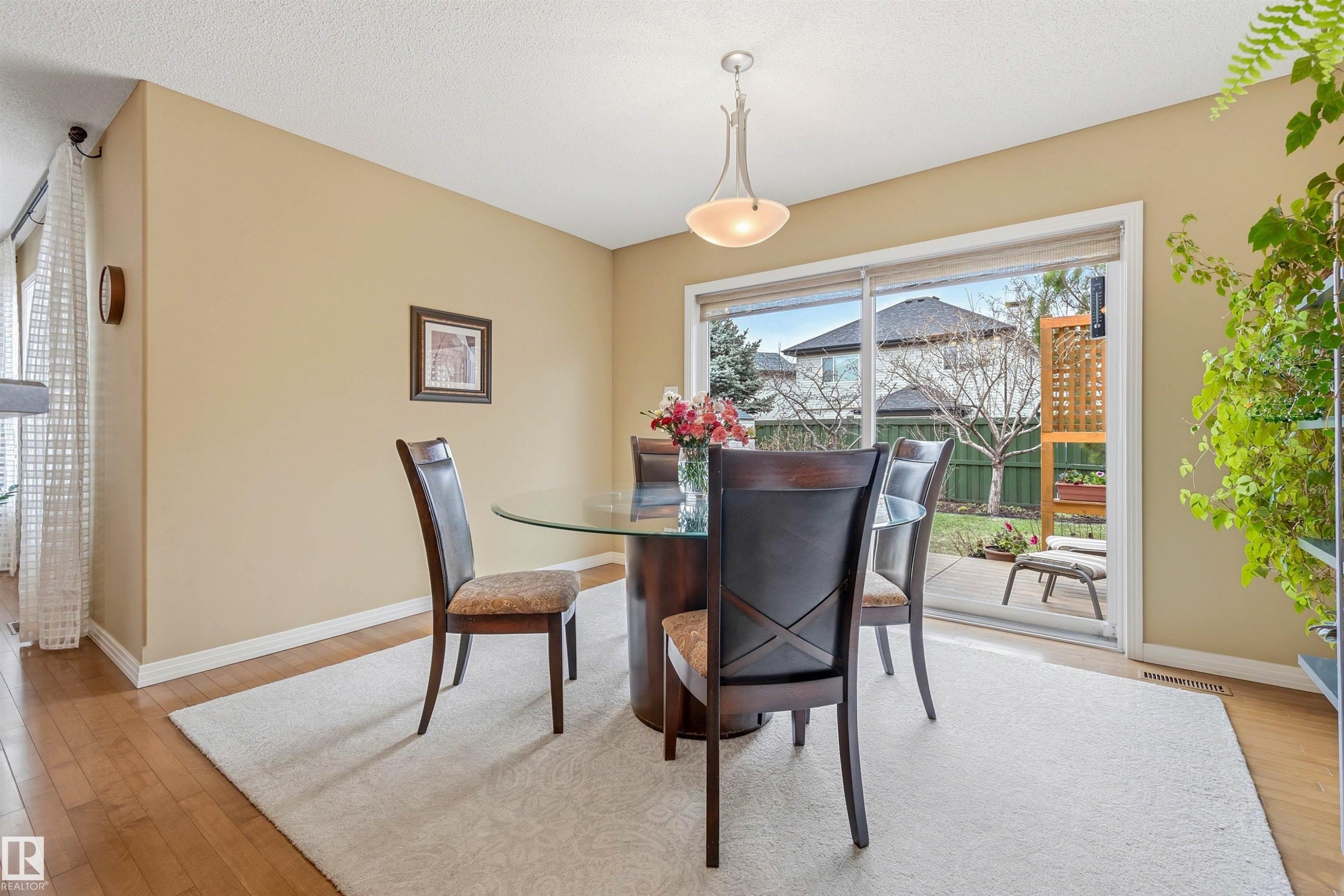 Dining area featuring wood-finish flooring, a contemporary ceiling fixture, and a sliding glass door providing direct access to the backyard patio - 2340 Hagen Link, Edmonton, AB - Indoor Photo Showing Dining Room